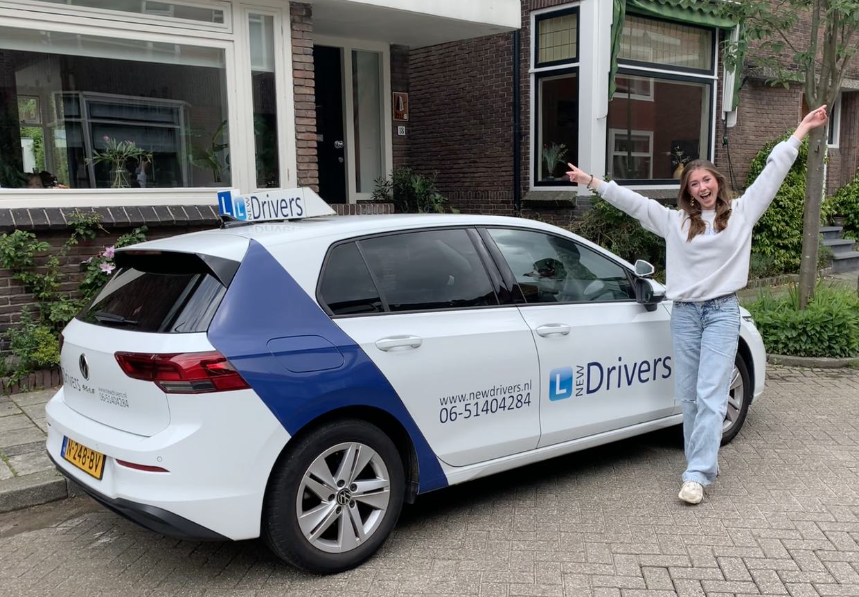 Geslaagde leerling van New Drivers naast de lesauto met New Drivers belettering in Waddinxveen