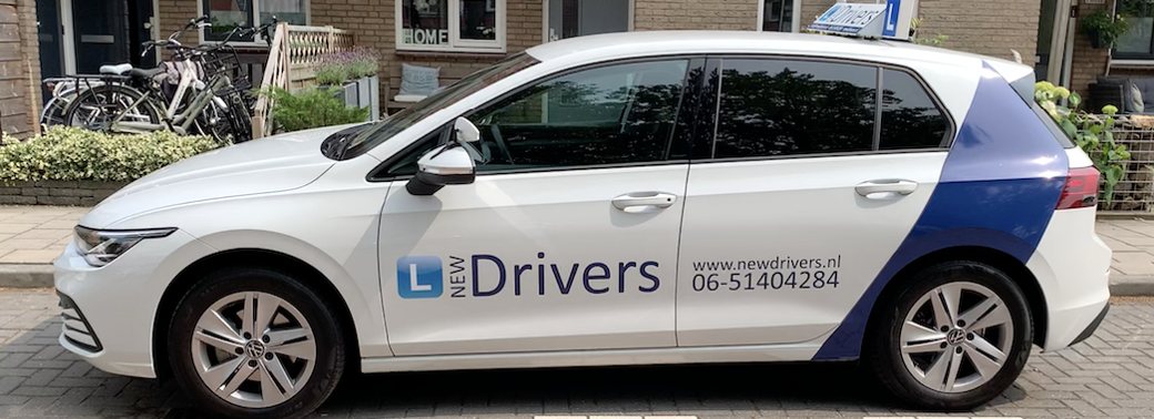 De lesauto van New Drivers, een witte Volkswagen Golf met blauwe belettering, naast de nieuwe Golf e-Hybrid 50 Edition